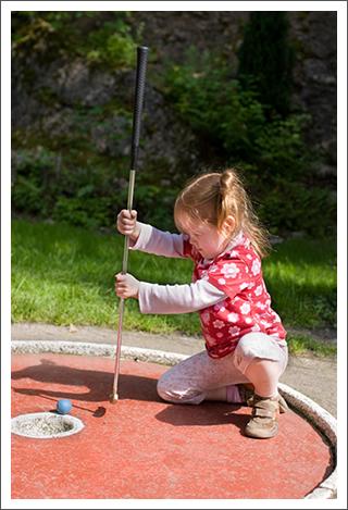 Little girl playing mini golf